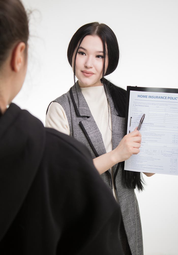 about-04 Young Asian businesswoman explaining home insurance policy to client, highlighting details with pen.