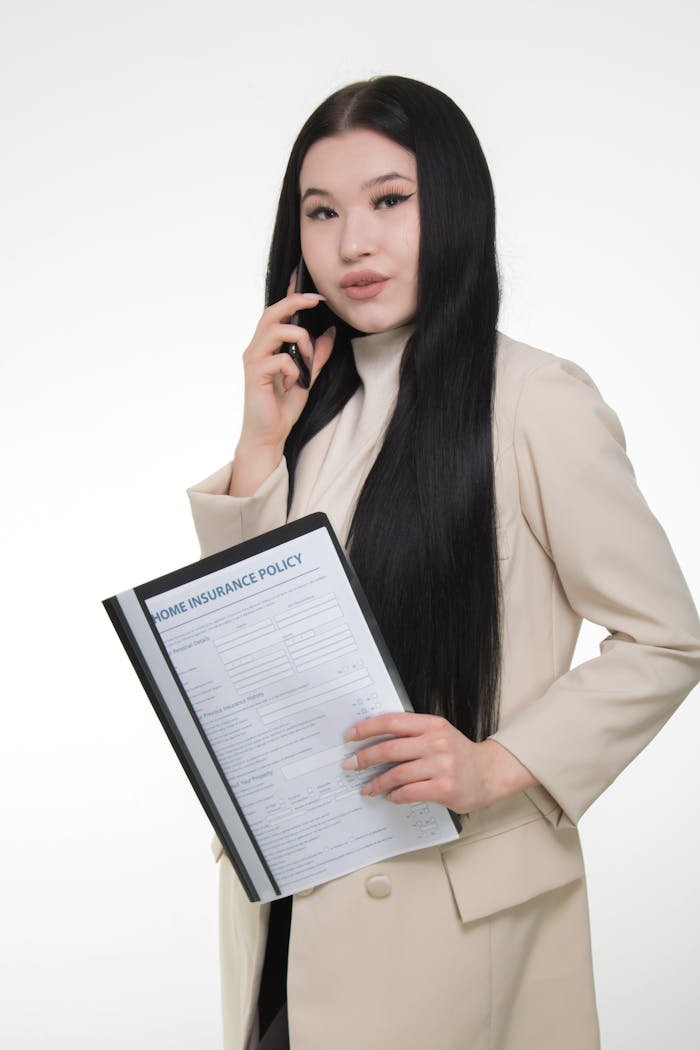 about-03 Confident woman in beige blazer holding a home insurance policy.