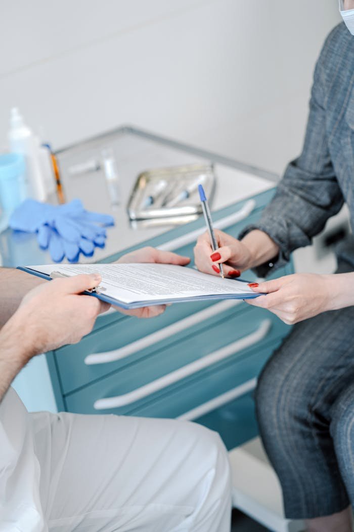 menu-03 Patient signing healthcare agreement in doctor's office, focus on hands and document exchange.