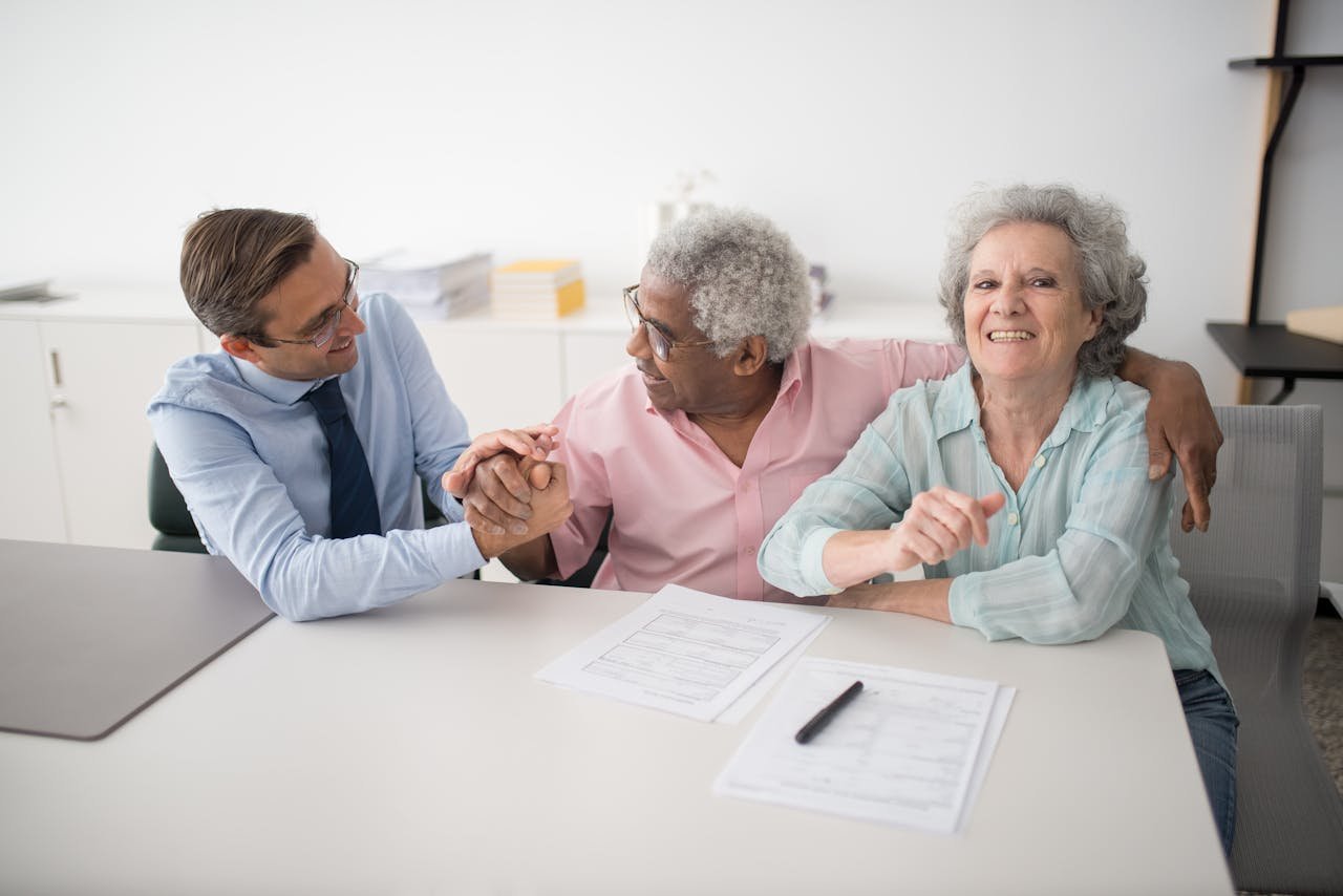 about-02 Senior couple in office meeting with consultant, discussing financial documents and smiling.